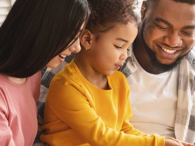 mum-in-pink-with-dad-in-white-reading-with-their-child-in-preschool-reading-tips-for-parents