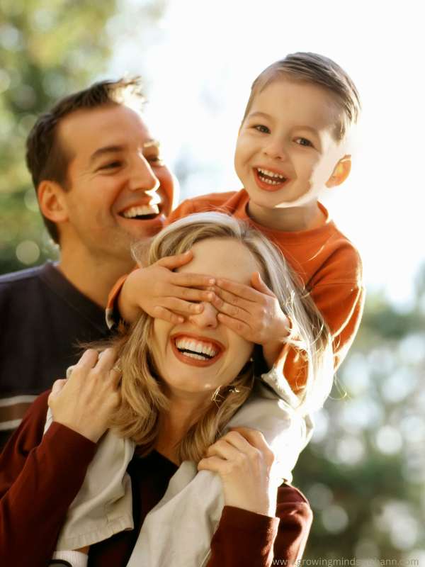 father-in-black-with-mum-in-brown-and-their-child-inorange-colour-covering-the-mother's-eye-in-10-common-parenting-mistake-to-avoid-in-your-child's-early-years
