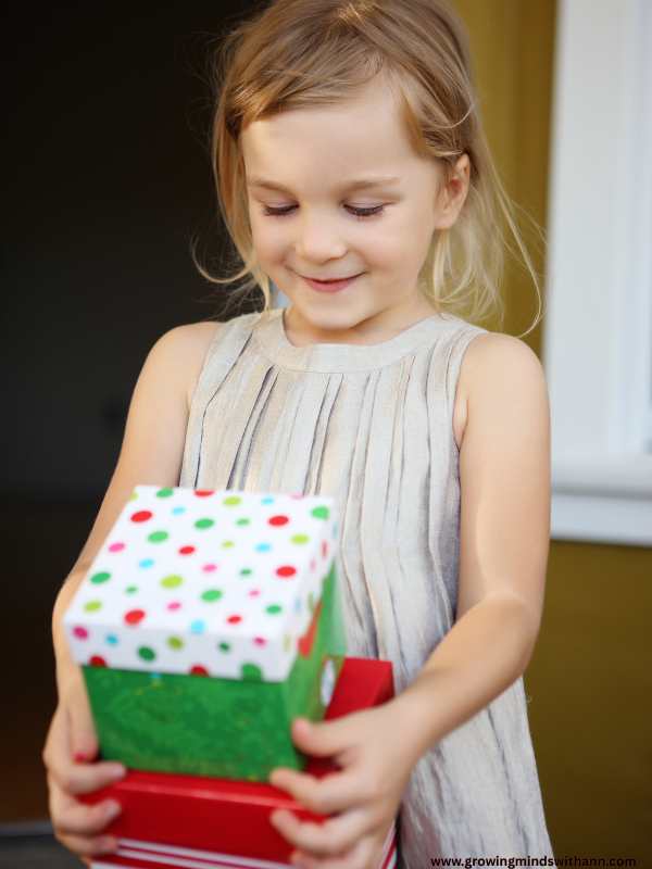 A-girl-holding-a-wrapped-gift-of-green-white-and-red-colours.