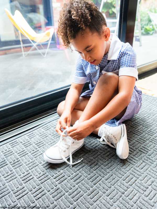 A-girl-in-blue-and-white-gown-tying-her-white-shoe-lace.