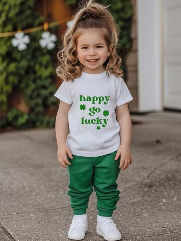 A-girl-wearing-white-polo-printed-happy-charm-with-green-trousers-and-white-sneakers-in-lovely-st-patrick's-day-kids-outfit-ideas.