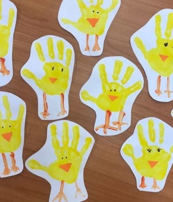 Handprint-chicks-made-from-yellow-handprint-on-white-paper-with-red-color-on-the-legs-and-mouth-and-blck-eye-in-fun-and-creative-spring-crafts-for-preschoolers.