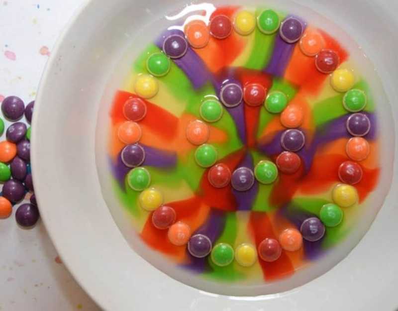 White-plate-containing-skittles-dissolved-in-water-to-produce-many-colors-in-fun-Easter-STEM-activities-for-kids.