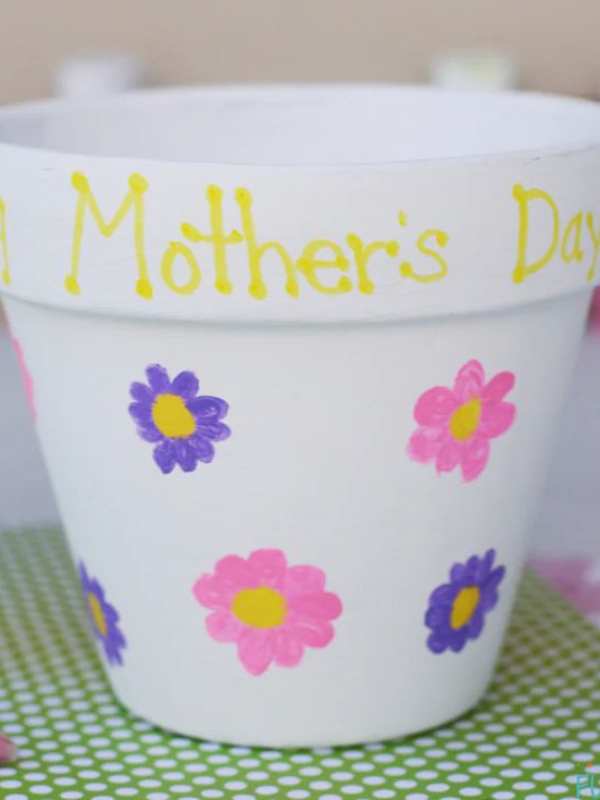 White-color-vase-designed-with-pink-blue-and-yellow-colors-with-mother's-day-written-on-top-of-it.