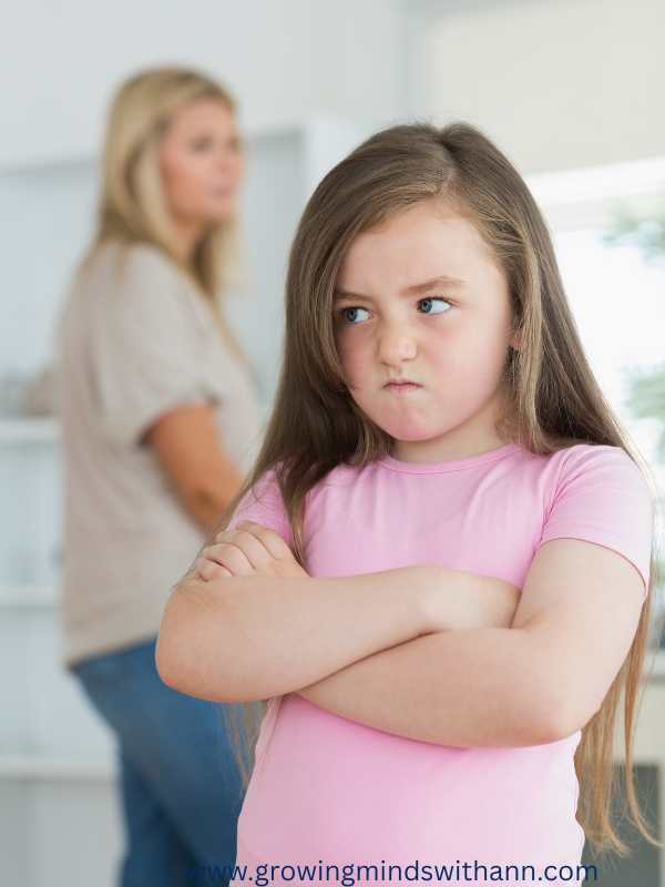 Girl-folding-her-2-hands-while-frowning-face-with-the-mom-behind-her.