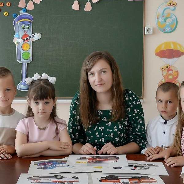 Teacher-sitting-in-the-middle-of-3-kids-with-papers-in-front-of-them-in-fun-classroom-activities-to-celebrate-teacher's-day.