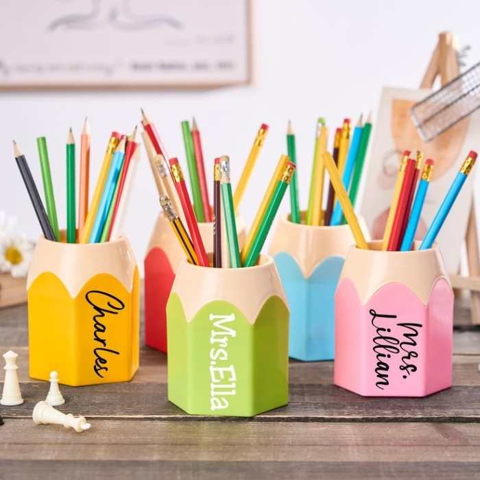 4-different-colors-of-pencil-holders-holding-about-8-10-pencils-each-with-different-names-written-on them.