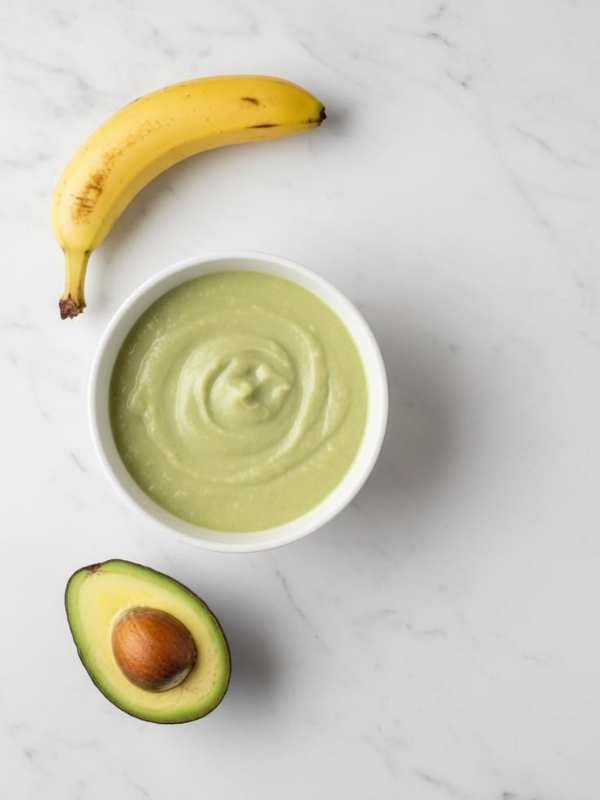 White-plate-containing-avocado-banana-puree-with-banana-and-avocado-beside-it-in-healthy-homemade-baby-puree-recipes-you-can-freeze.
