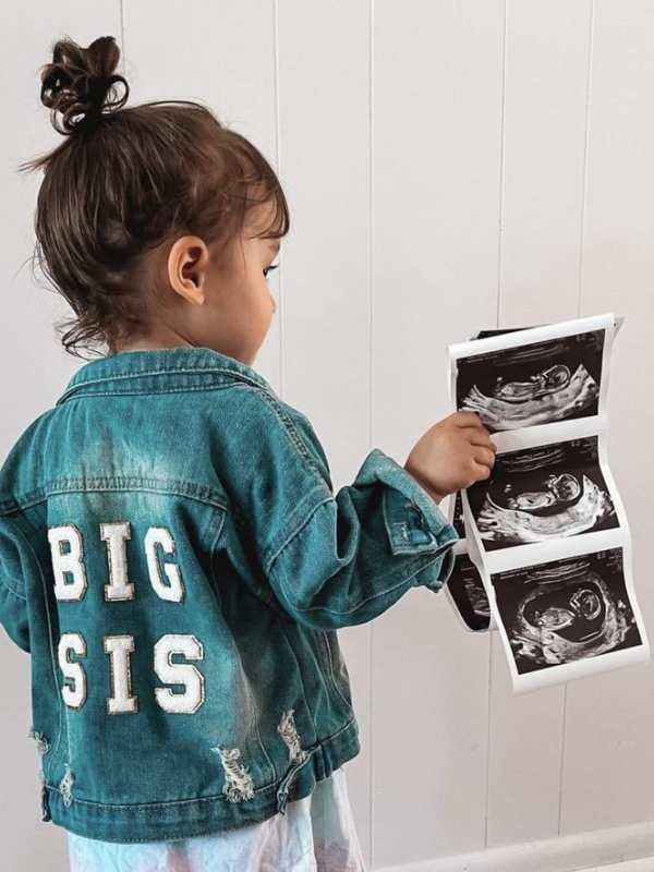 Girl-wearing-a-cloth-written-big-sis-at-the-back-holding-ultrasound-result.
