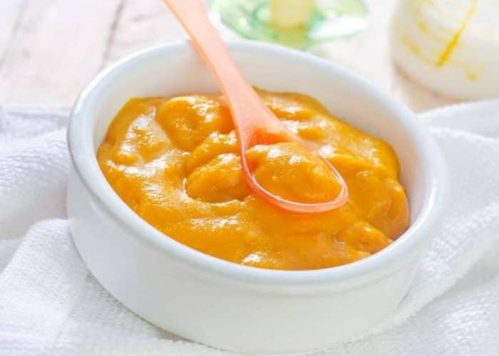 White-plate-containing-carrot-puree-with-pink=spoon-in-it.