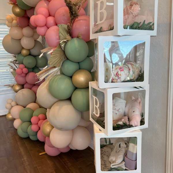 Different-colors-of-balloon-tied-as-arch-with-4-transparent-glass-box-written-baby-in-cute-and-affordable-tropical-baby-shower-theme-ideas.