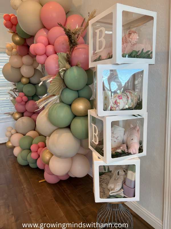 Different-colors-of-balloon-tied-as-arch-with-4-transparent-glass-box-written-baby-in-cute-and-affordable-tropical-baby-shower-theme-ideas.