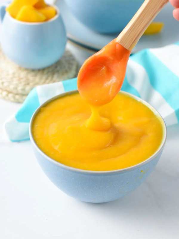 Blue-pate-containing-mango-banana-puree-with-orange-sppon-in-in-it.