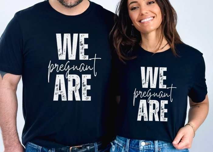 Husband-and-wife-wearing-black-matching-T-shirt-written-we=are-pregnant.