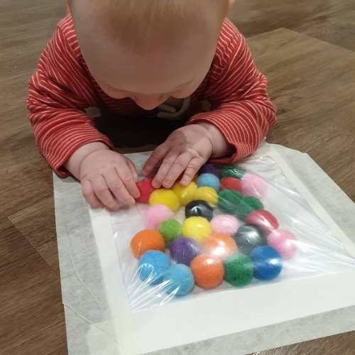 Child-exploring-pom-pom-sensory-bag-in-easy-sensory-activities-for-toddlers-and-preschoolers.