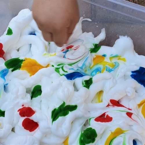 Hand-playing-with-shaving-cream-in-a-bin.