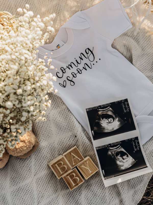 Ultrasound-photo-baby-cloth--and-shoes-lay-flat-on-a-white-surface-in-super-creative-pregnancy-announcement-ideas.