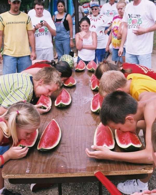 3-girls-and-3-boys-eating-water-melon-from-a-table-without-touching-it-in-fun-4th-of-july-games-your-family-will-love.