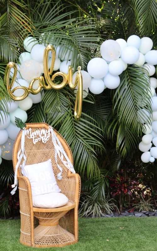 Palm-front-with-white-balloon-arch-round-the-top-and-chair-beside-it.