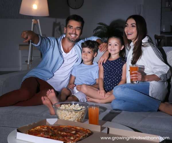 Mom-dad-and-their-2-kids-watching-movie-at-night.
