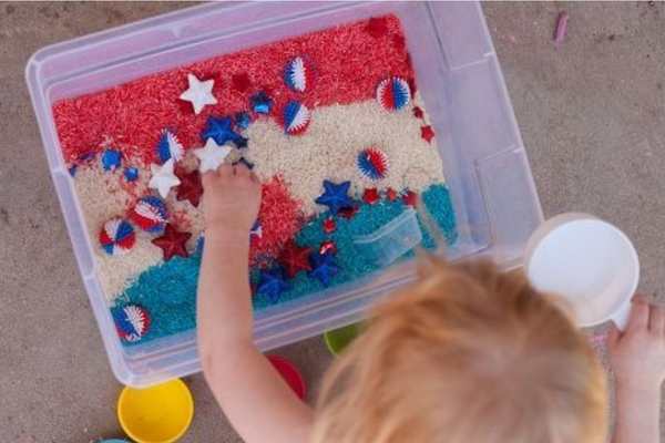 Child-playing-with-red-white-and-blue-rice-sensory-bin-in-4th-of-July-sensory-bin-easy-patriotic-sensory-play-for-kids.