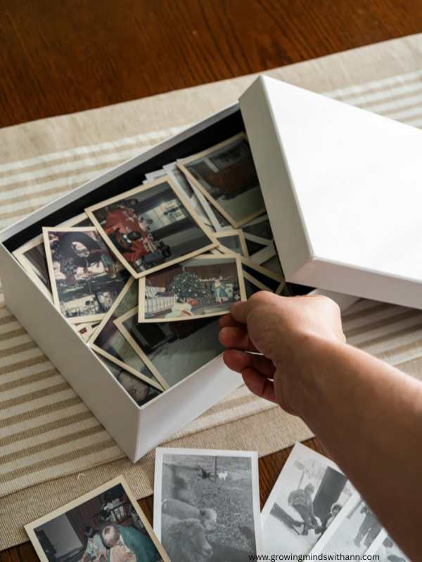 Box-filled-with-different-photos-with-hands-bringing-out-the-photos-in-Family-Memory-Box-Ideas-To-Preserve-our-Precious-Memories.