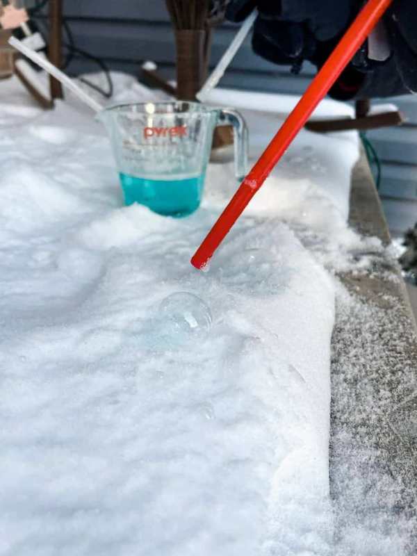 Kids-using-straw-to-blow-snow-bubbles-in-screen-free-snow-day-activities-for-toddlers.