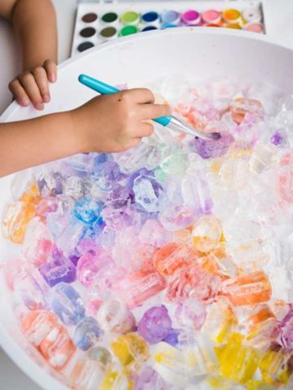 Hand-painting-ice-in-a-bin-with-different-colors.