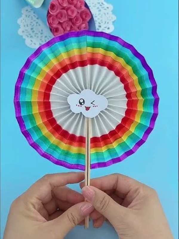 Hand-holding-rainbow-paper-fan-in-summer-crafts-for-kids.