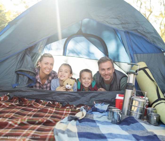Mom-dad-and-kids-in-a-tent-with-flask-and-mat-beside-the-tent-in-summer-bucket-list-ideas-for-families.