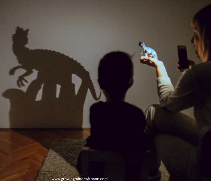 Mother-flashing-light-on-a-toy-to-create-shadow-from-it-while-the-chilld-is-watching-in-low-prep-homeschooling-activities-for-busy-moms.