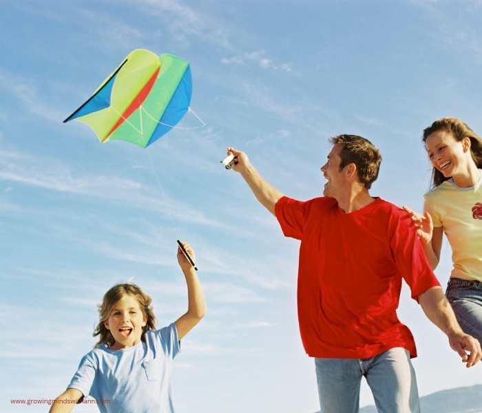 Dad-holding-a-flying-kite-while-the-son-and-wife-run-towards-him.