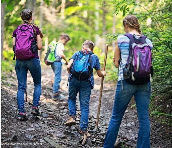 Family-of-four-on-a-nature-hike-with-bags-on-their-back.