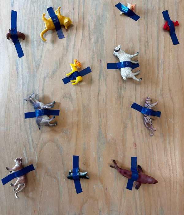 Different-types-of-toys-sticked-on-a-flat-surface-with-tape-in-masking-tape-activities-for-toddlers-that-are-easy-and-fun.