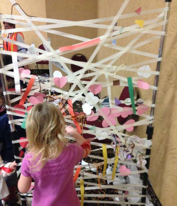 Toddler-sticking-different-colors-of-pare-shapes-on-a-sticky-wall-art.