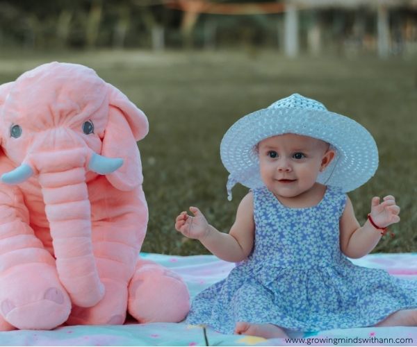Baby-sitting-beside-elephant-toy-in-baby-photoshoot-ideas-at-home.