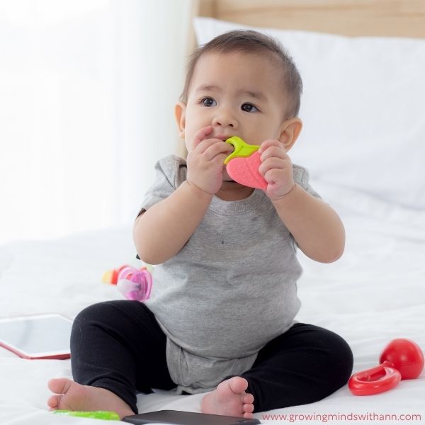 Baby-sitting-down-while-holding-a-toy-in-baby-photoshoot-ideas-at-home.