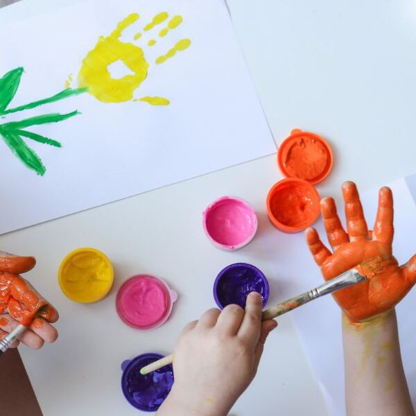Kids-painting-their-hands-to-create-flower-in-fall-handprint-crafts-for-toddlers-and-preschoolers.