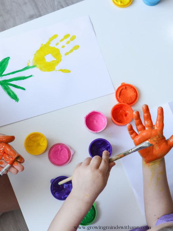 Kids-painting-their-hands-to-create-flower-in-fall-handprint-crafts-for-toddlers-and-preschoolers.