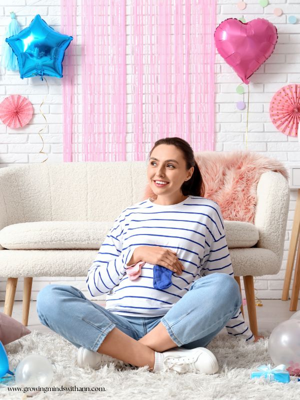 Mom-sitting-on-the-floor-while-holding-blue-and-pink-socks-in-gender-reveal-outfit-ideas-for-mom-to-be.