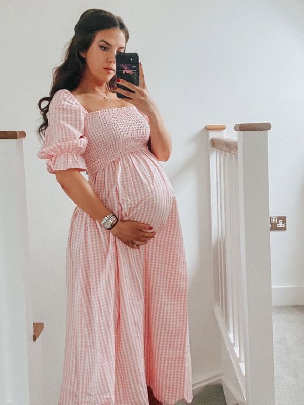 Woman-wearing-pink-gingham-dress-in-gender-reveal-outfit-ideas-for-mom-to-be.