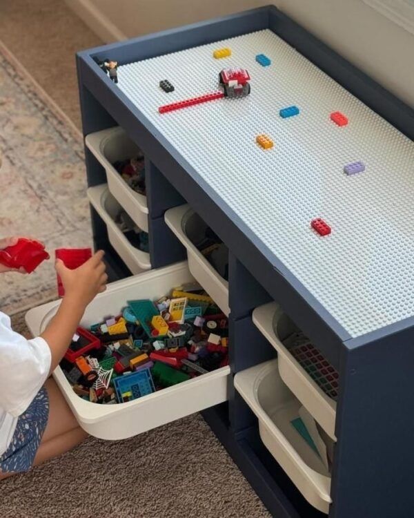 Boy-bringing-out-toys-from-LEGO-table-with-built-in-compartments.