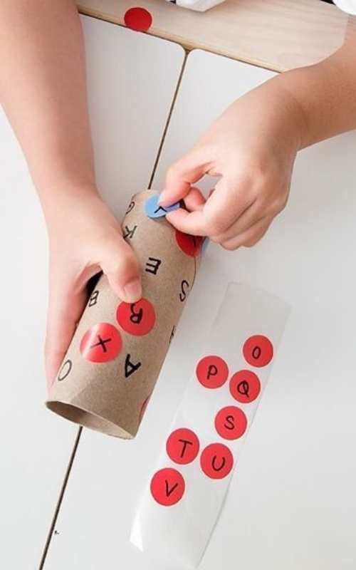 Child-sticking-letter-sticker-on-a-toilet-paper-roll-in-fun-ways-to-teach-the-alphabet-to-preschoolers