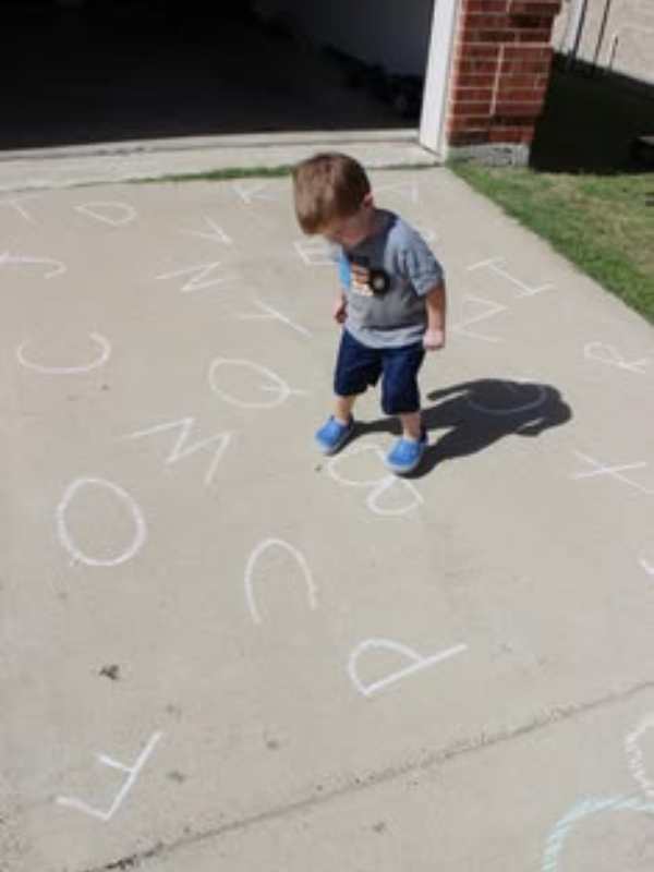 Child-playing-with-sidewalk-alphabet.