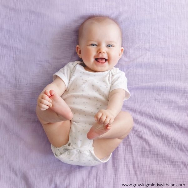 Baby-on-the-bed-smiling-and-holding-two-feet-with-two-hands.