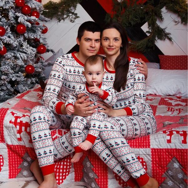Mom-dad-and-baby-wearing-Christmas-pajamas-sitting-close-to-a-Christmas-tree-in-Christmas-traitions-to-start-with-your-baby.