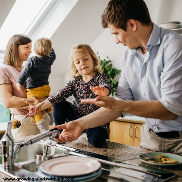 Dad-and-daughter-washing-plate-while-mom-and-son-are-watching.