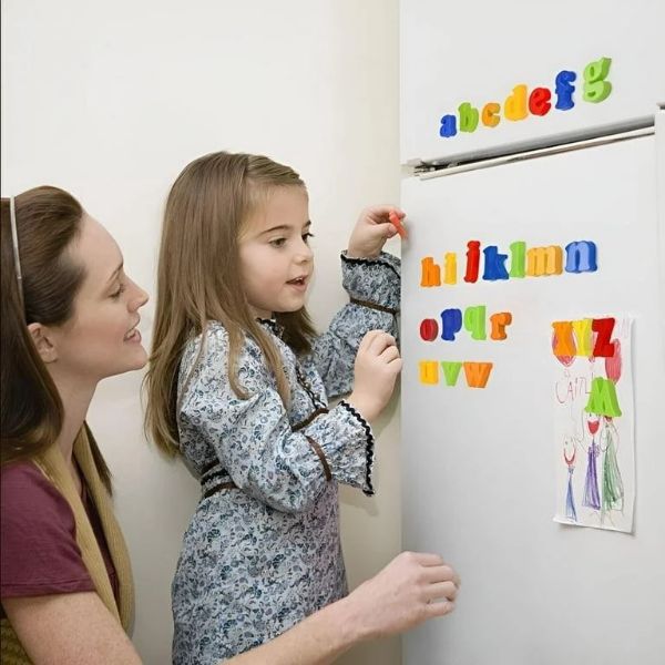 Mom-watching-daughter-build-her-name-with-alphabet-magnet.